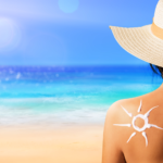 Fotoprotezione - donna in spiaggia, con cappello e crema solare