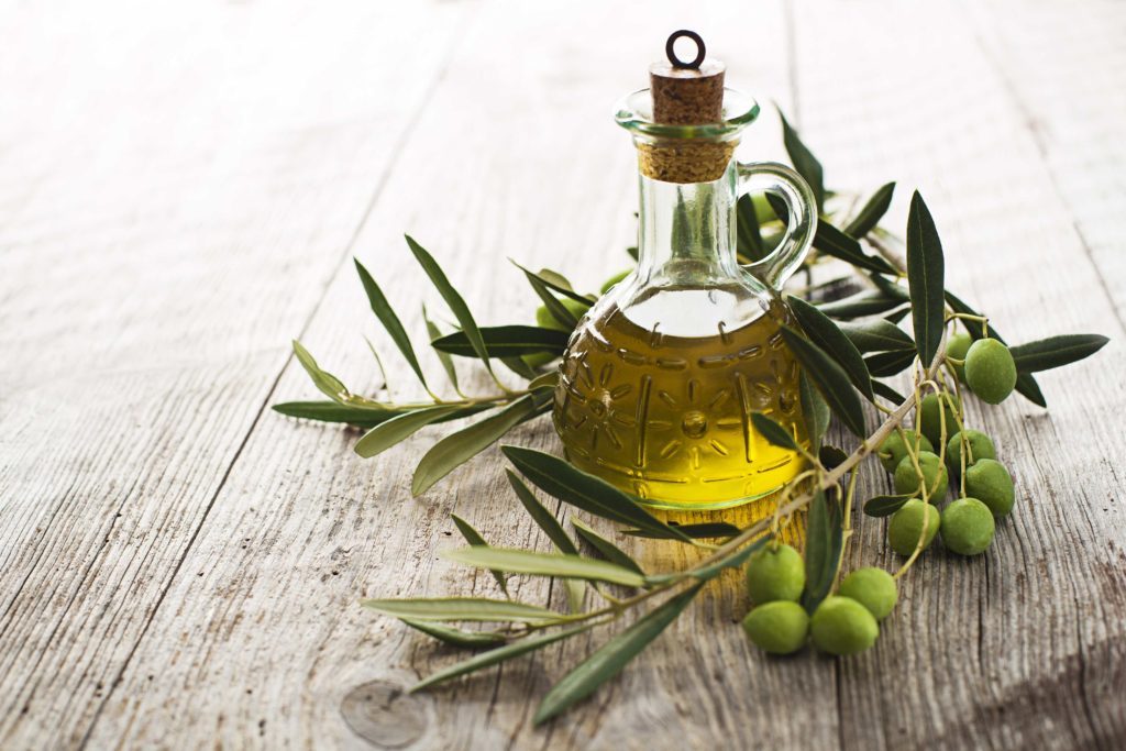 Olio extravergine di oliva - bottiglietta con olio extraverginde d'oliva, circondata da un ramoscello coi frutti