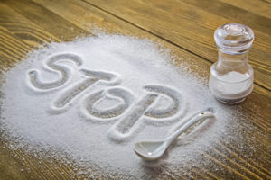Ridurre il sale da cucina - scritta "stop" nel sale rovesciato sul tavolo